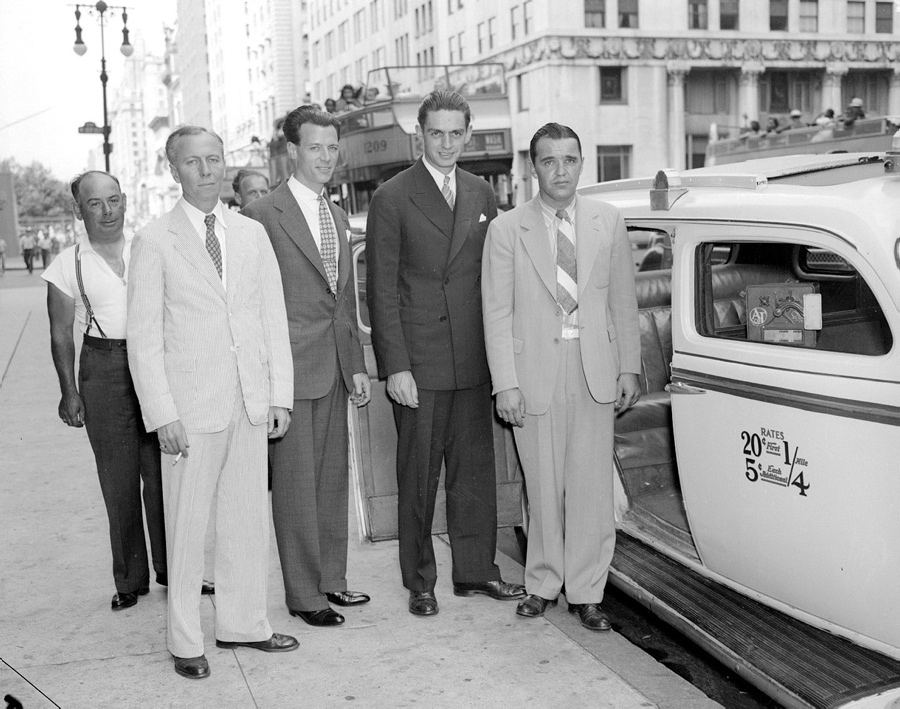Crew members of Howard Hughes' successful around the world flight stand outside of a New York City taxicab. The crew includes radio man Richard Stoddart, flight engineer Edward Lund, navigator Harry Connor, and co-pilot Thomas Thurlow.
