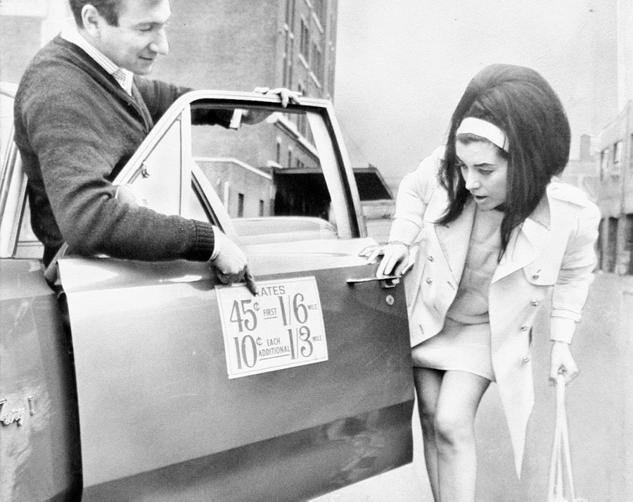 Taxi driver George Wells shows Darlene Larson the rates for a cab ride.