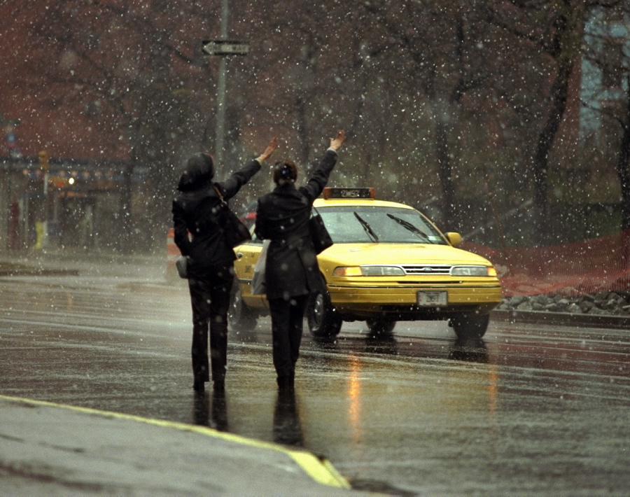 Two women try to hail a cab on Houston Street in the midst of a downpour.