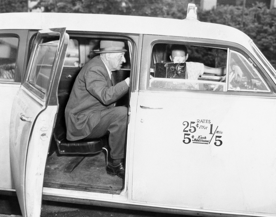 Hack Bureau Inspector Louis Salerno seals taxicab meter after testing its adjustment to new rates. Inspector John Dunnigan rode in cab to watch adjusted meter.