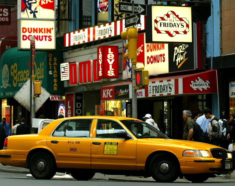 A yellow cab makes a turn at the intersection of John St. and Broadway downtown.