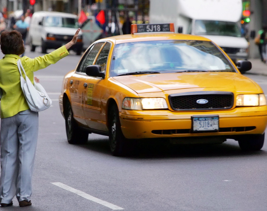 A woman tries to hail a taxicab on Eighth Ave. on the morning a 48-hour strike began. The number of cabbies on strike, protesting the installation of GPS tracking systems and credit card machines, is disputed and those still working picked up multiple passengers, charging flat-fares based on zones.